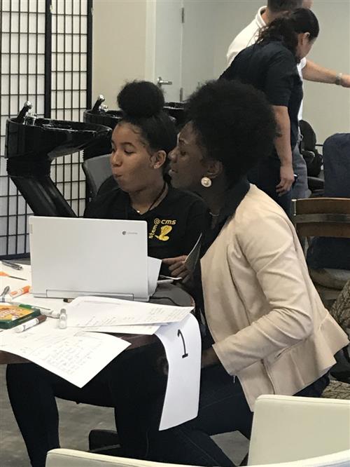 STEM student girl sits with woman mentor working on Manufacturing Day project. 